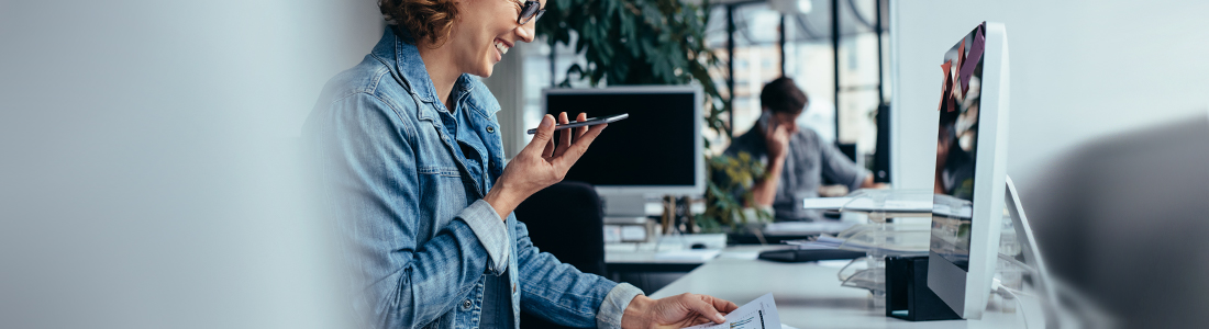 User holding a mobile phone while looking at desktop