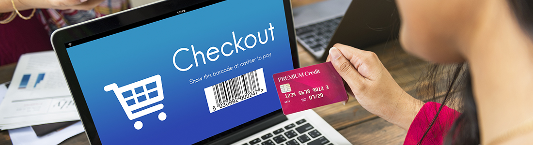 A woman holding a credit card in front of the laptop