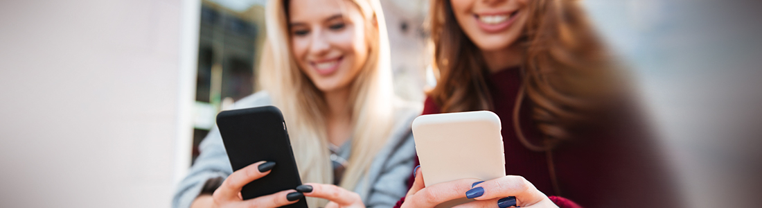 two women holding mobile phones and smiling