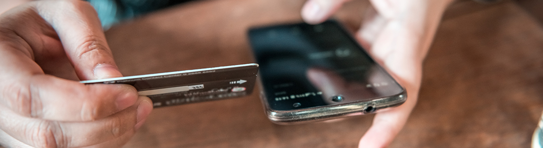 A person holding a credit card while using a mobile phone