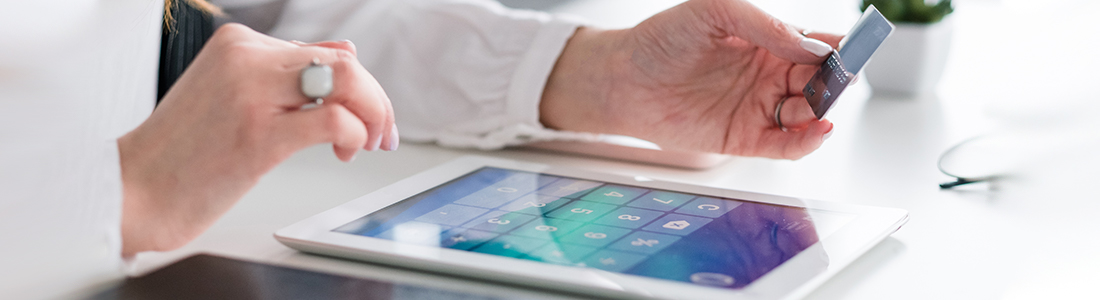 someone holding a credit card and deciding on different payment platforms on a tablet]