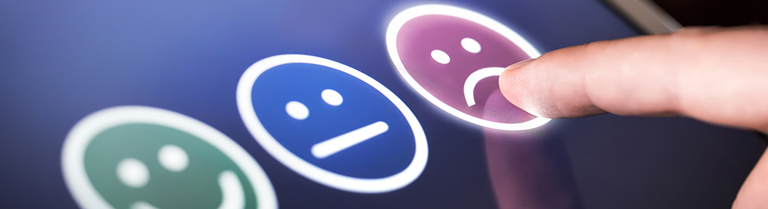 A customer choosing the dissatisfied emoji on a tablet screen 